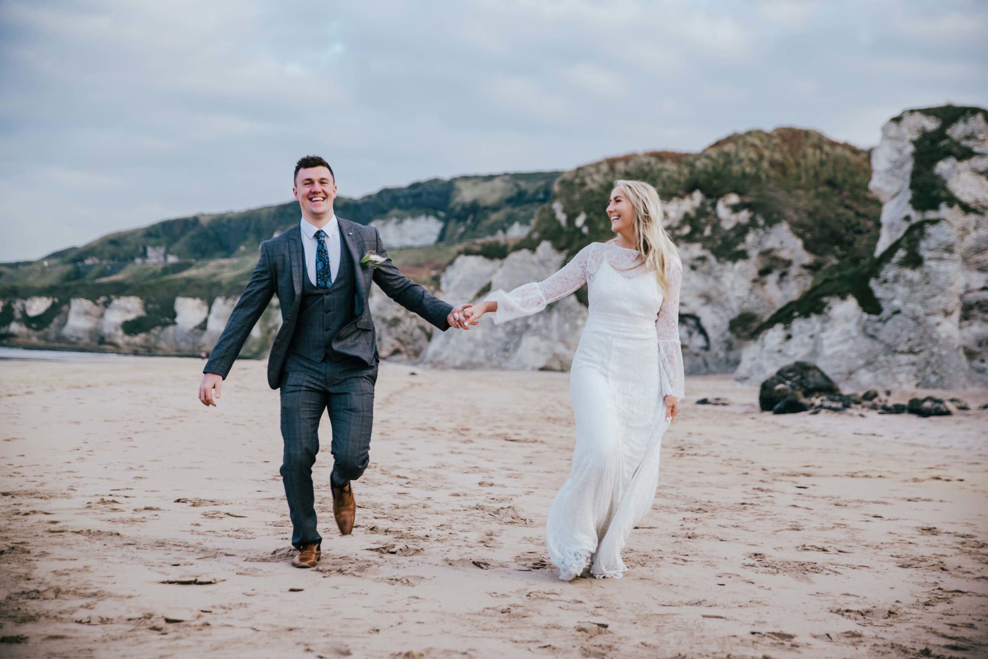 Wedding, bride, and groom walking at the beach . Wedding photographer london