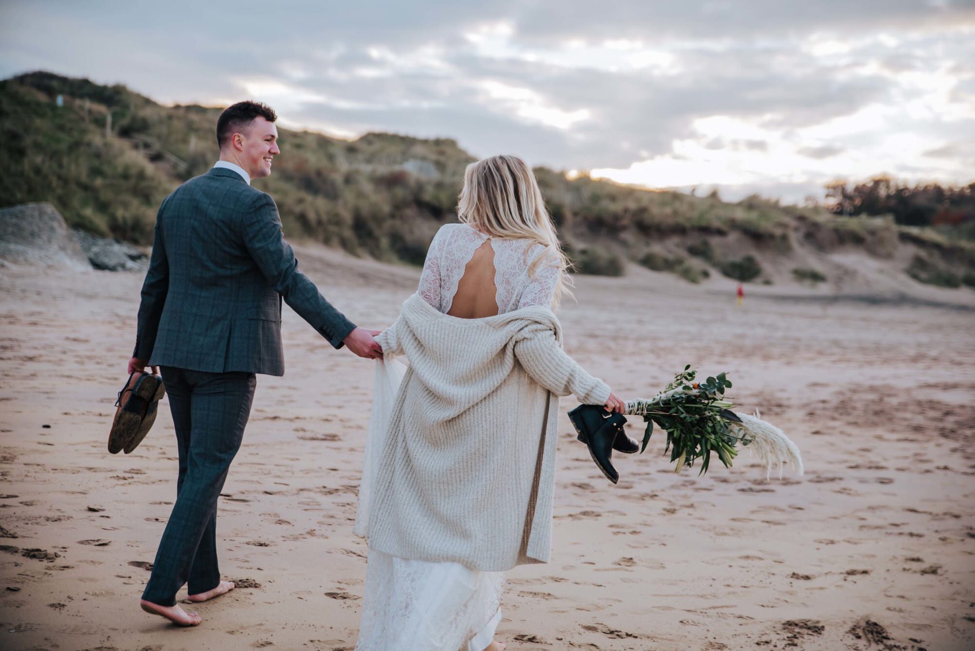 Wedding, bride, and groom walking at the beach . Wedding photographer london