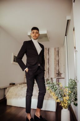 Groom ready to go, wearing balck turtle neck and coat, black trousers
