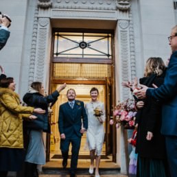 Katya in silk vintage weddign dress, Brett in blue suit at the Old Marylebone registry office London confetti shot