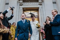 Katya in silk vintage weddign dress, Brett in blue suit at the Old Marylebone registry office London confetti throwing at the entrance