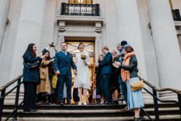 Katya in silk vintage weddign dress, Brett in blue suit at the Old Marylebone registry office London confetti throwing at the entrance