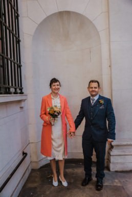 Katya in silk vintage weddign dress, Brett in blue suit at the Old Marylebone registry office London couples shot at the entrance
