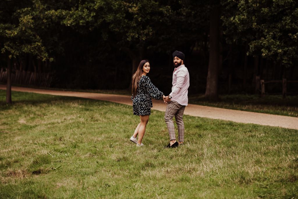 Couple looking back near a river at the Painshill Park Surrey engagement shoot