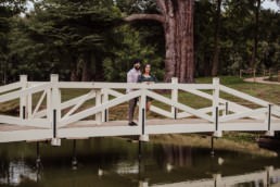 Couple hugging on the bridge near a river at the Painshill Park Surrey engagement shoot