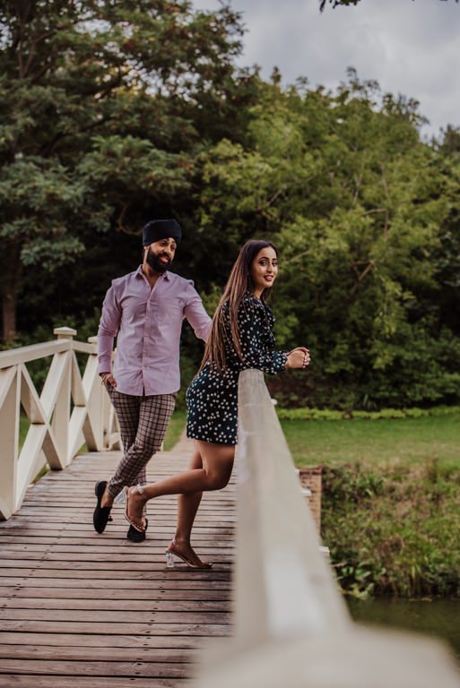 Couple standing on the bridge near a river at the Painshill Park Surrey engagement shoot