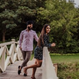 Couple standing on the bridge near a river at the Painshill Park Surrey engagement shoot