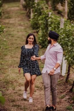 Couple walking through the vineyard near a river at the Painshill Park Surrey engagement shoot