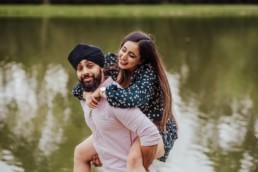 boyfriend piggy backing his girlfriend near a river at the Painshill Park Surrey engagement shoot