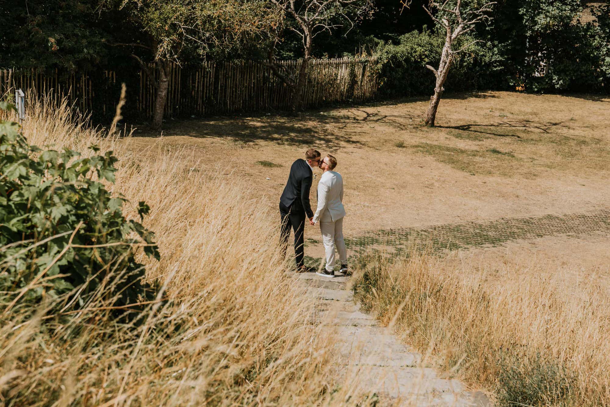two grooms kissing in the steps of a hill