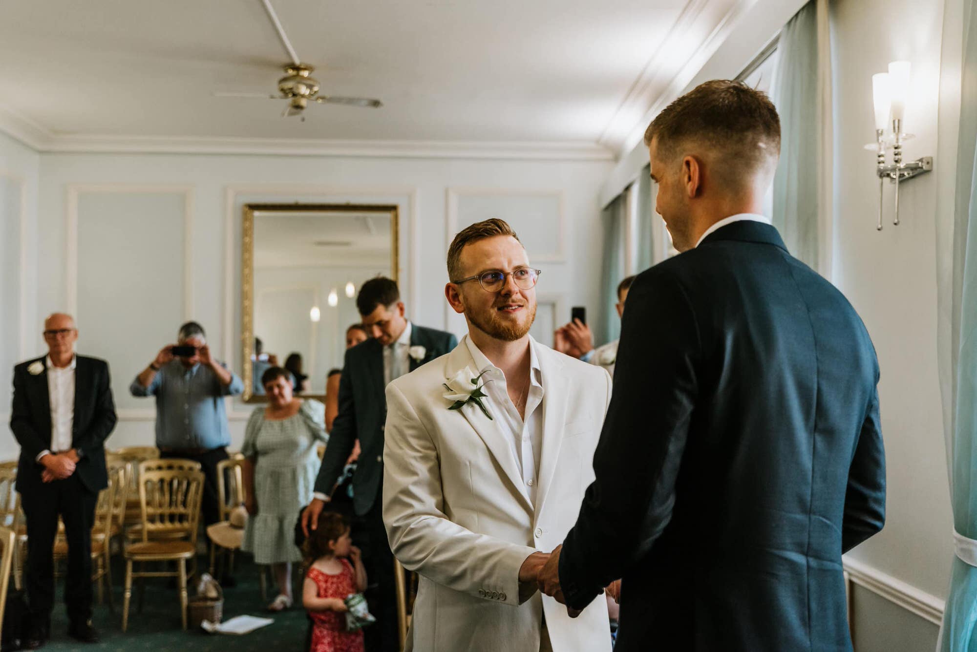 grooms looking at each other, guests at the back